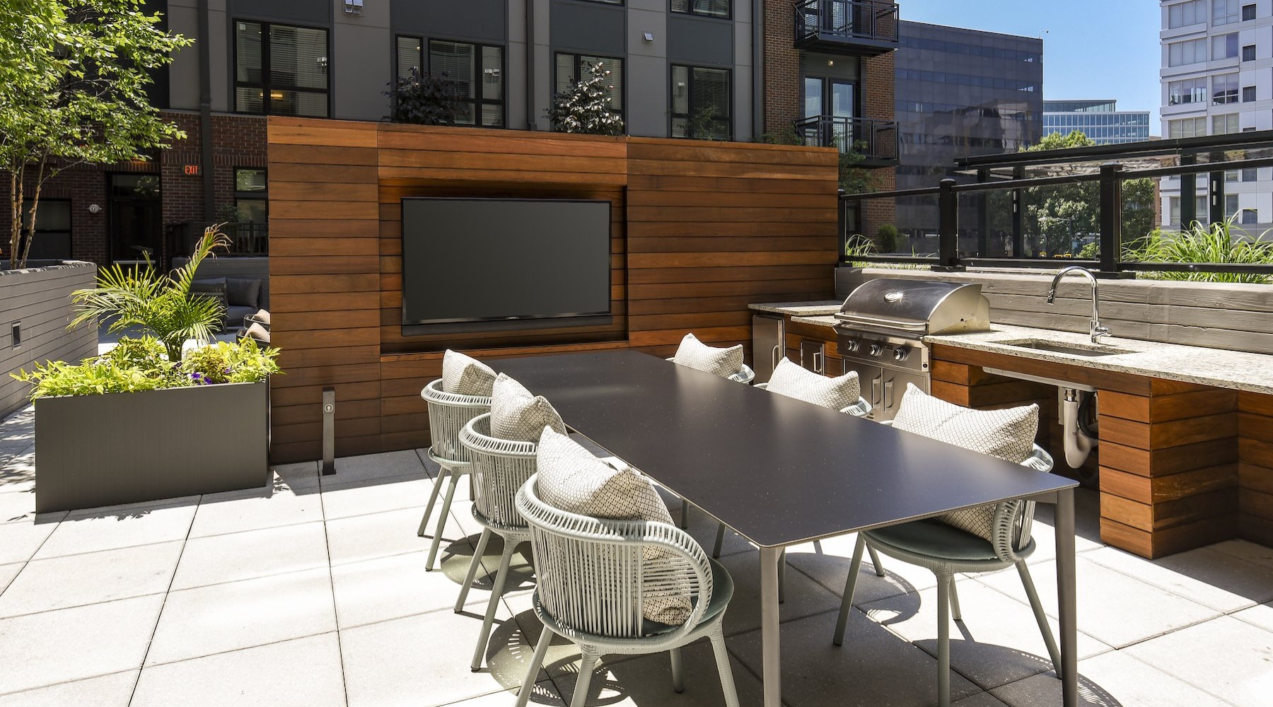 a grill area with a tv, table and chairs